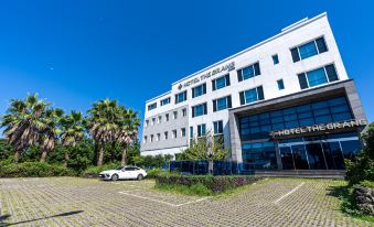 The apartment complex has large windows and a front view that can be seen from across a parking lot at Hotel the Grang Jungmun