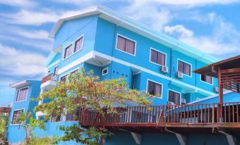 a blue building with white trim and balconies is surrounded by green trees , under a blue sky at Hotel Playa Bonita