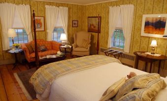 a cozy bedroom with yellow walls , white curtains , and a large bed decorated with pillows and blankets at Three Mountain Inn