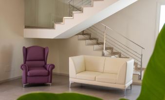 a modern living room with white and purple furniture , including a couch , armchair , and coffee table at Hotel Royal