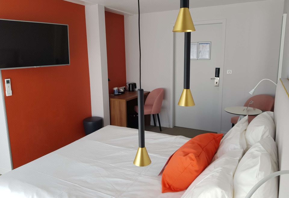a hotel room with a bed , desk , and tv , decorated in white and orange colors at Kyriad Lyon Est - Saint Quentin Fallavier