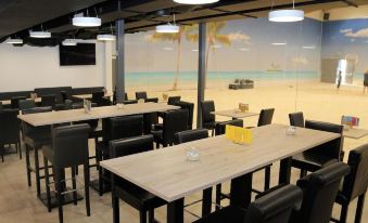 a dining area with multiple tables and chairs , some of which are arranged around a large window overlooking the ocean at Beachin - Sport, Events, Hotel, Restaurant, Bar