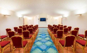 a long room with rows of red chairs and a blue and white patterned carpet at Hotel Santa Gilla