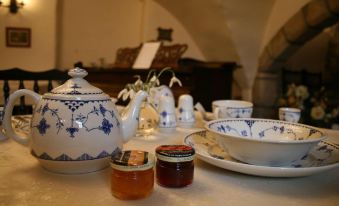 a dining table with a blue and white tea set , including a teapot , cups , and saucers , accompanied by several small bottles at Leslie Castle