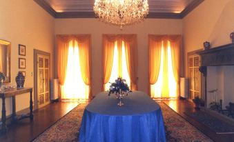 a large room with a round table covered in a blue tablecloth and a chandelier hanging from the ceiling at Villa Alta - Residenza d'Epoca Con Piscina