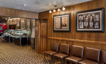 a room with wooden walls and a tiled floor has several chairs , framed photos on the wall , and framed portraits at Best Western Dunmar Inn
