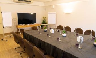 a conference room with a long table covered in a gray tablecloth , surrounded by chairs and a television at Lux* Grand Gaube