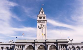 a clock tower with a flag flying on top , standing in front of a blue sky at Four Points by Sheraton - San Francisco Bay Bridge