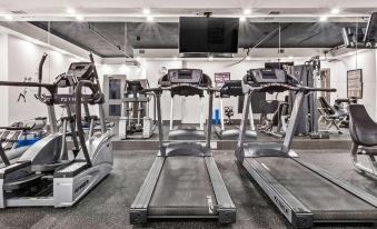 a gym with several treadmills and exercise bikes , along with a television mounted on the wall at Best Western Plus Pontoon Beach