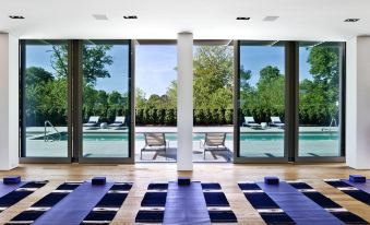 a room with multiple yoga mats arranged in rows , surrounded by windows that provide a view of a pool and lounge chairs at Topping Rose House