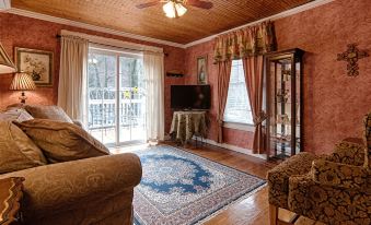 a cozy living room with wooden furniture , a tv , and a couch , along with a large window that overlooks the outdoors at Broad River Inn