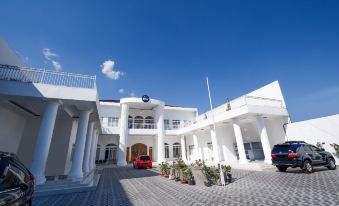 a white building with a red car parked in front and blue skies above at Griya RW Family Guest House Redpartner