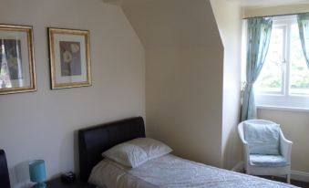 a bedroom with a bed , chair , and window , featuring a white comforter and pillows on the bed at The Shoes