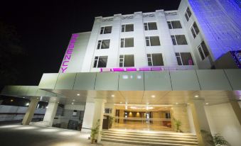 a large hotel building at night , with its name displayed in pink lights and white walls at Regency Tirunelveli By GRT Hotels
