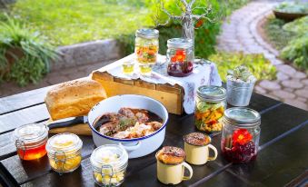 a wooden table is set with various jars , a pot of soup , and some bread at Morning Glory Cottages