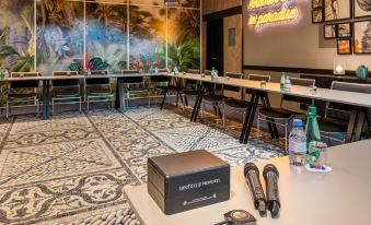 a conference room with tables , chairs , and keyboards , decorated with neon signs and various items such as audio - visual equipment at Novotel Paris 14 Porte d'Orleans