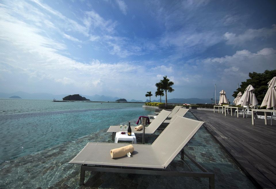 a beach scene with several lounge chairs placed on the edge of a large body of water at Resorts World Langkawi