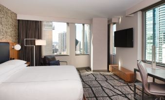 a modern hotel room with a large window offering a city view , white bed , and black leather furniture at The Charter Hotel Seattle, Curio Collection by Hilton