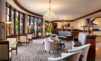 a large , well - lit room with a piano in the center and several chairs surrounding it at Hotel Grand Pacific