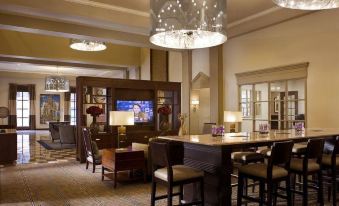 a large , well - lit hotel lobby with a bar and dining area , as well as comfortable seating arrangements at New Haven Hotel