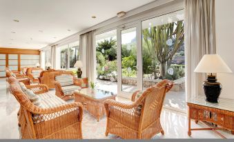 a spacious living room with wicker furniture and large windows , providing a view of the outdoors at Grupotel Molins