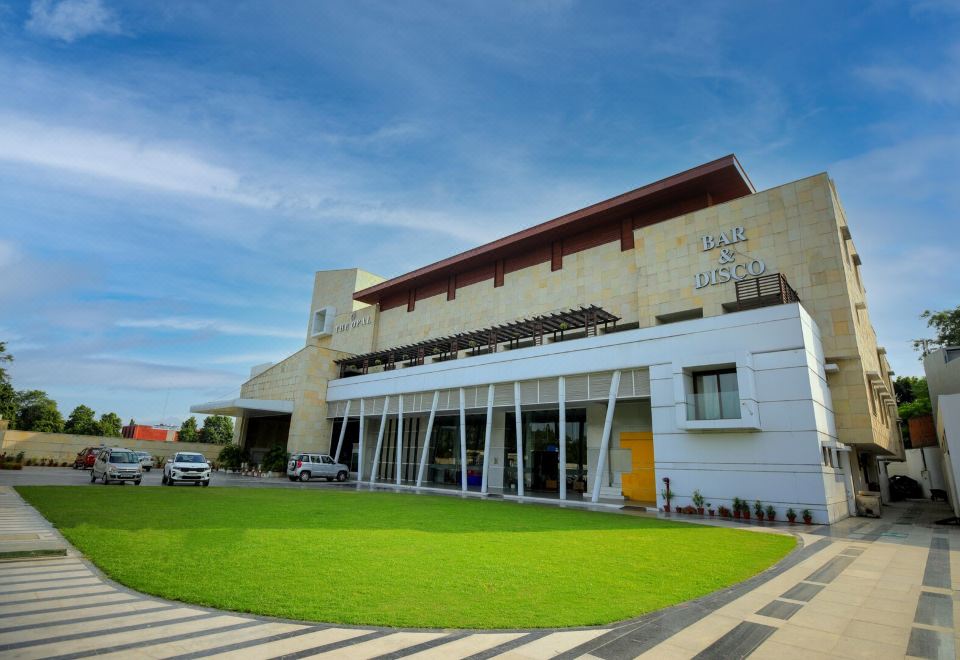 a large white building with a green lawn in front of it , surrounded by trees at The Opal