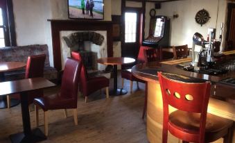 a cozy bar with wooden floors , a fireplace , and a tv mounted on the wall at Polochar Inn