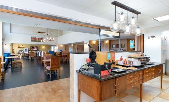 a dining area with a wooden counter , multiple chairs , and a kitchen counter filled with food at Hampton Inn & Suites Pittsburg