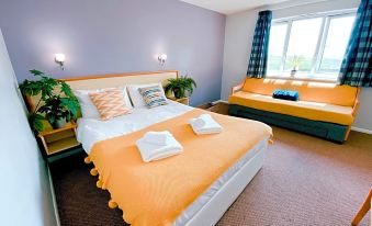 a hotel room with two beds , one of which is an orange bed and the other is a purple bed at Redwings Lodge Rutland