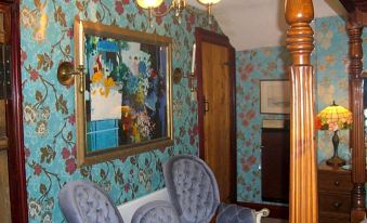 a room with floral wallpaper , blue chairs , and a wooden door , as well as a chandelier hanging from the ceiling at Ash Farm Country House