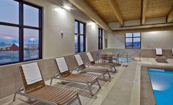 a row of wooden lounge chairs with cushions is situated in a room with large windows at Shoshone Rose Casino & Hotel