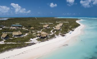 a beach with clear blue water and white sand , surrounded by trees and various buildings at Anegada Beach Club