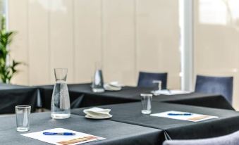 a conference room set up for a meeting , with tables and chairs arranged in rows at Hotel Nagusi