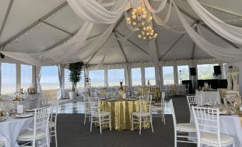 a well - decorated event space with white chairs and tables , draped in gold tablecloths and draped over chandeliers at Rod 'N' Reel Resort