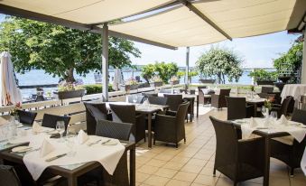 an outdoor dining area with a variety of chairs and tables , creating a pleasant atmosphere for guests at Seehotel Leoni