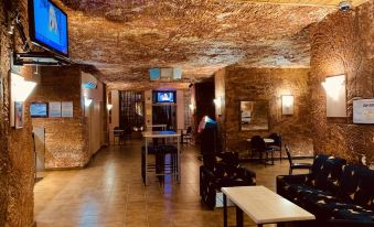 a room with exposed brick walls and a wooden ceiling has a television mounted on the wall at Desert Cave Hotel