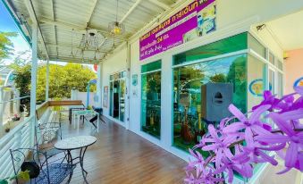 "a white building with a green awning , featuring a sign in front of it that says "" flower "" and an advertisement for "" central barbershop" at The Linux Garden Hotel