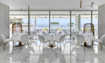 a large , modern dining room with white chairs and tables set up for a meal at Ivi Mare - Designed for Adults by Louis Hotels