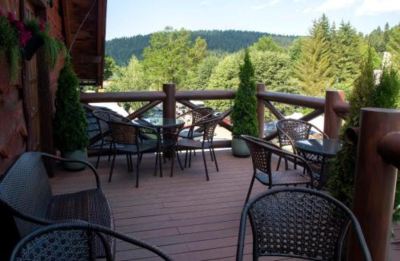 a wooden deck with several chairs and tables , overlooking a forested area and mountains in the background at Troll