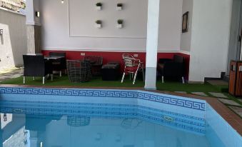 There is an indoor swimming pool surrounded by chairs and tables in the middle at Millennium Apartments