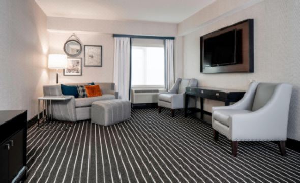 a well - furnished living room with various pieces of furniture , including a couch , chairs , and a television at Courtyard Boston Brookline