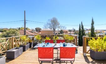 a wooden deck with a dining table and chairs set up for a meal , surrounded by greenery at Dade