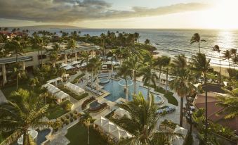 an aerial view of a resort with a pool , palm trees , and ocean in the background at Four Seasons Resort Maui at Wailea