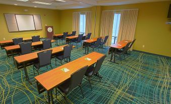 a conference room with wooden tables and chairs , a podium , and curtains on the windows at SpringHill Suites Hershey Near the Park