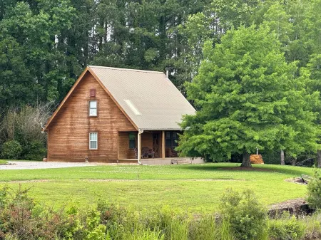 Cozy Cabin setting behind a 1 1/2 acre pond that is lined with Cypress Trees.
