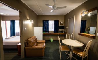 a living room with a couch , dining table , and kitchen in the background , all decorated in warm colors at Ardeanal Motel