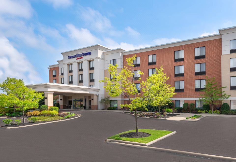 "a large brick hotel building with a blue sign that reads "" hampton inn & suites .""." at SpringHill Suites Cleveland Solon
