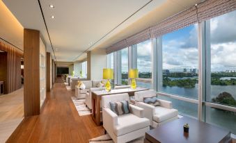 a modern lounge area with white sofas and wooden floors , large windows offering views of the city at Lotte Hotel Yangon