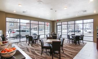 a large room with multiple tables and chairs , a car parked outside , and large windows at Cobblestone Hotel & Suites - Two Rivers