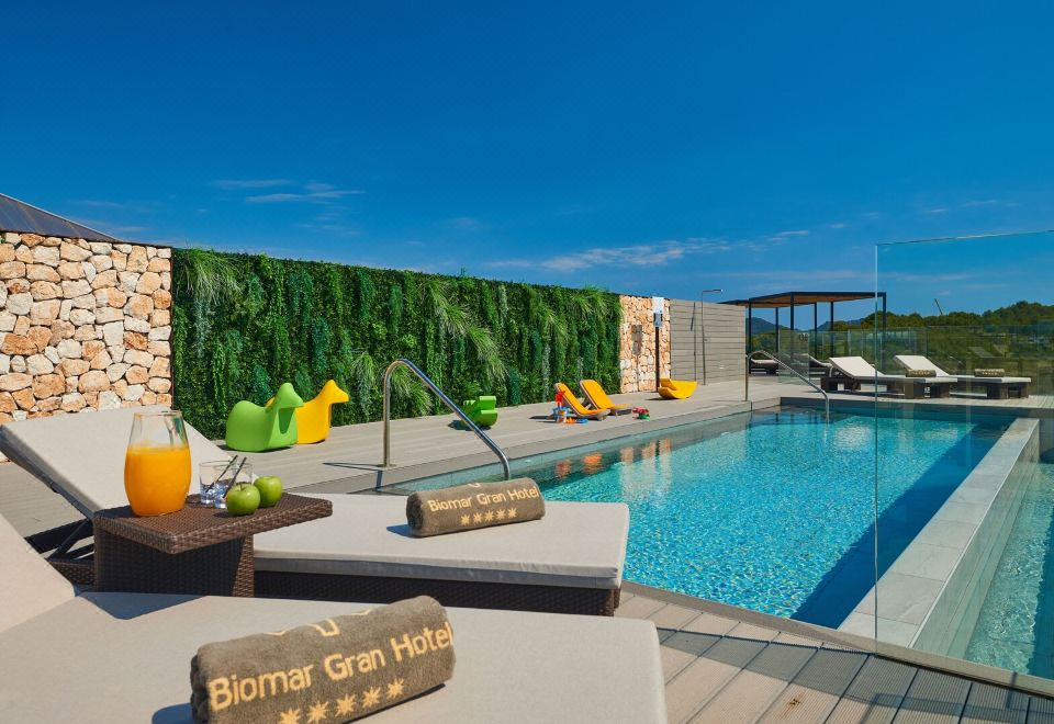 a large swimming pool surrounded by a deck , with several lounge chairs and umbrellas placed around it at Protur Biomar Sensatori Resort